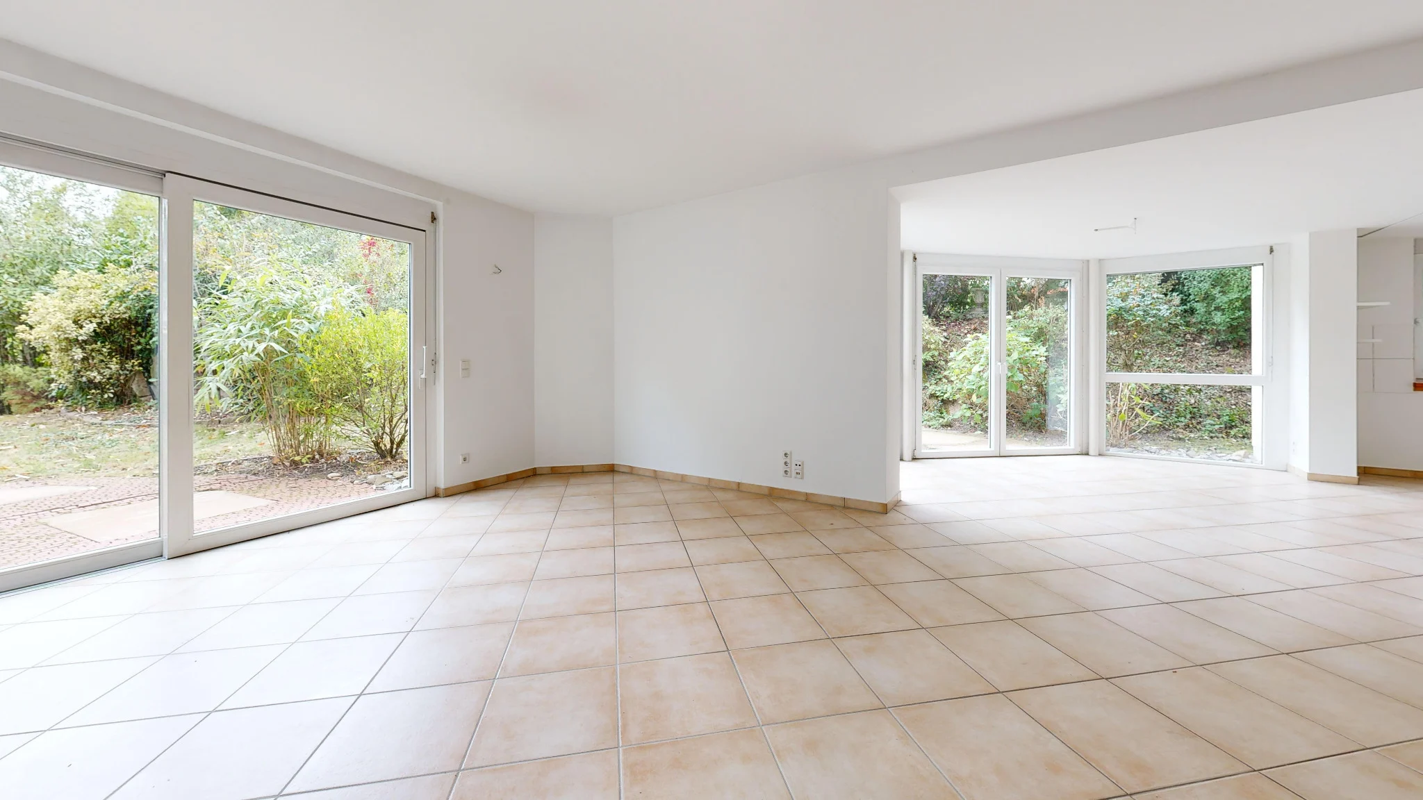 Heller Wohnbereich mit großen Fensterflächen und Zugang zu Terrasse und Garten
